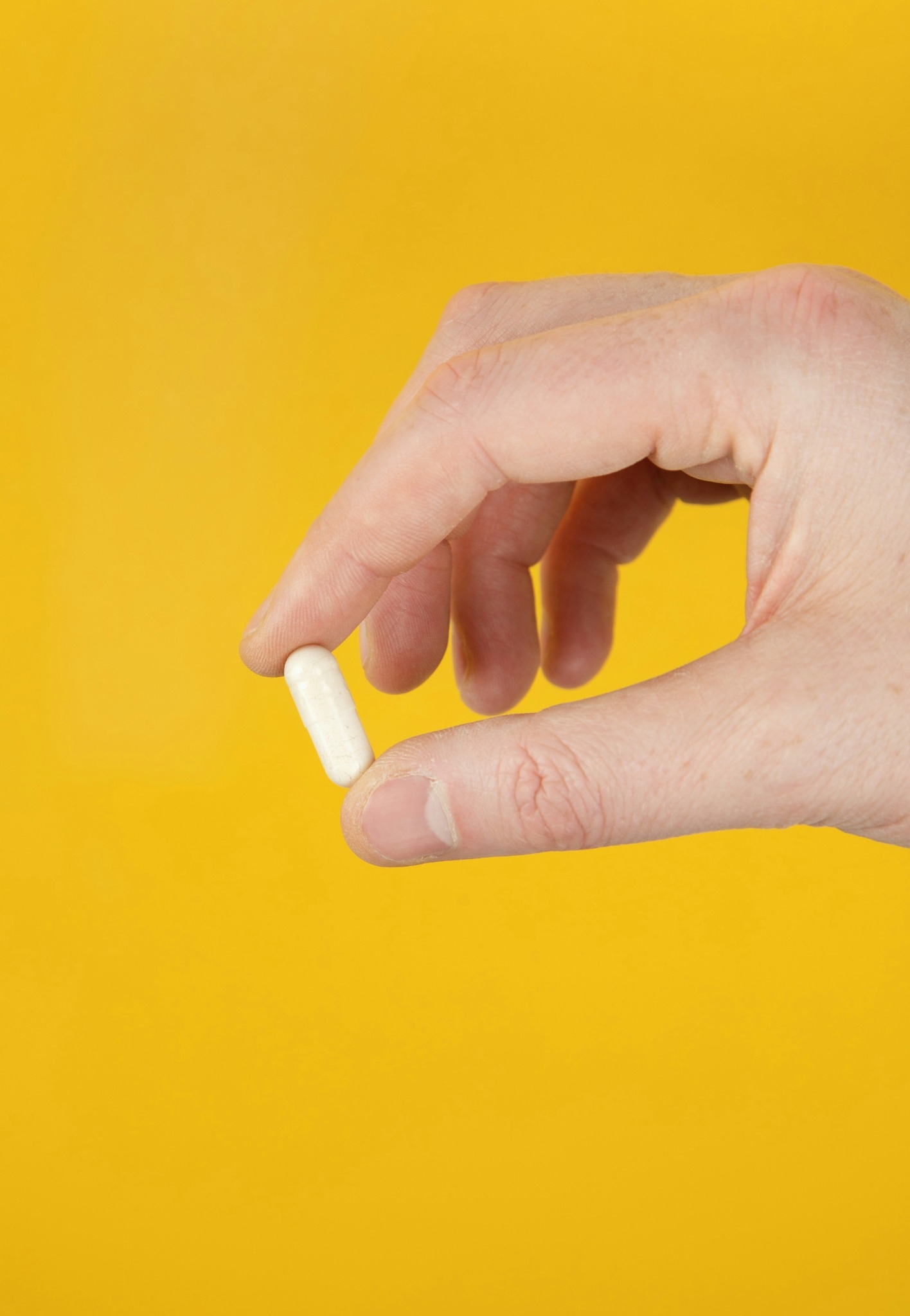 una mano sostiene una pastilla entre sus dedos